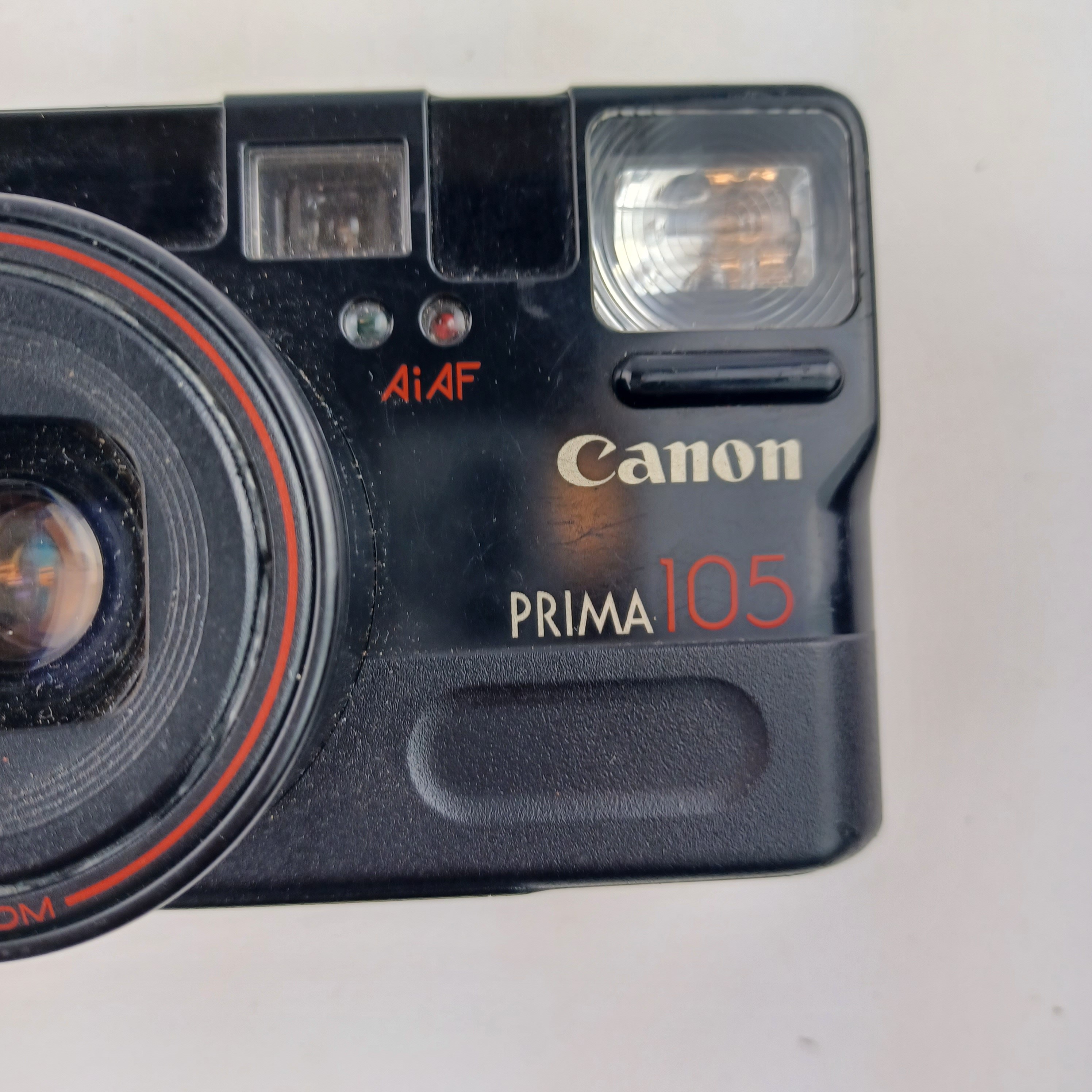 Voir photo 4 de Appareil photo Canon Prima 105 avec batterie lithium KL2CR5 sans chargeur, pellicule dedans, zoom 35-105, flash intégré, mode yeux rouges, retardateur et rafale, avec pochette et mode d'emploi Appareil photo Canon Prima 105 avec batterie lithium KL2CR5 sans chargeur, pellicule dedans, zoom 35-105, flash intégré, mode yeux rouges, retardateur et rafale, avec pochette et mode d'emploi Très bon état reconditionné photo 4