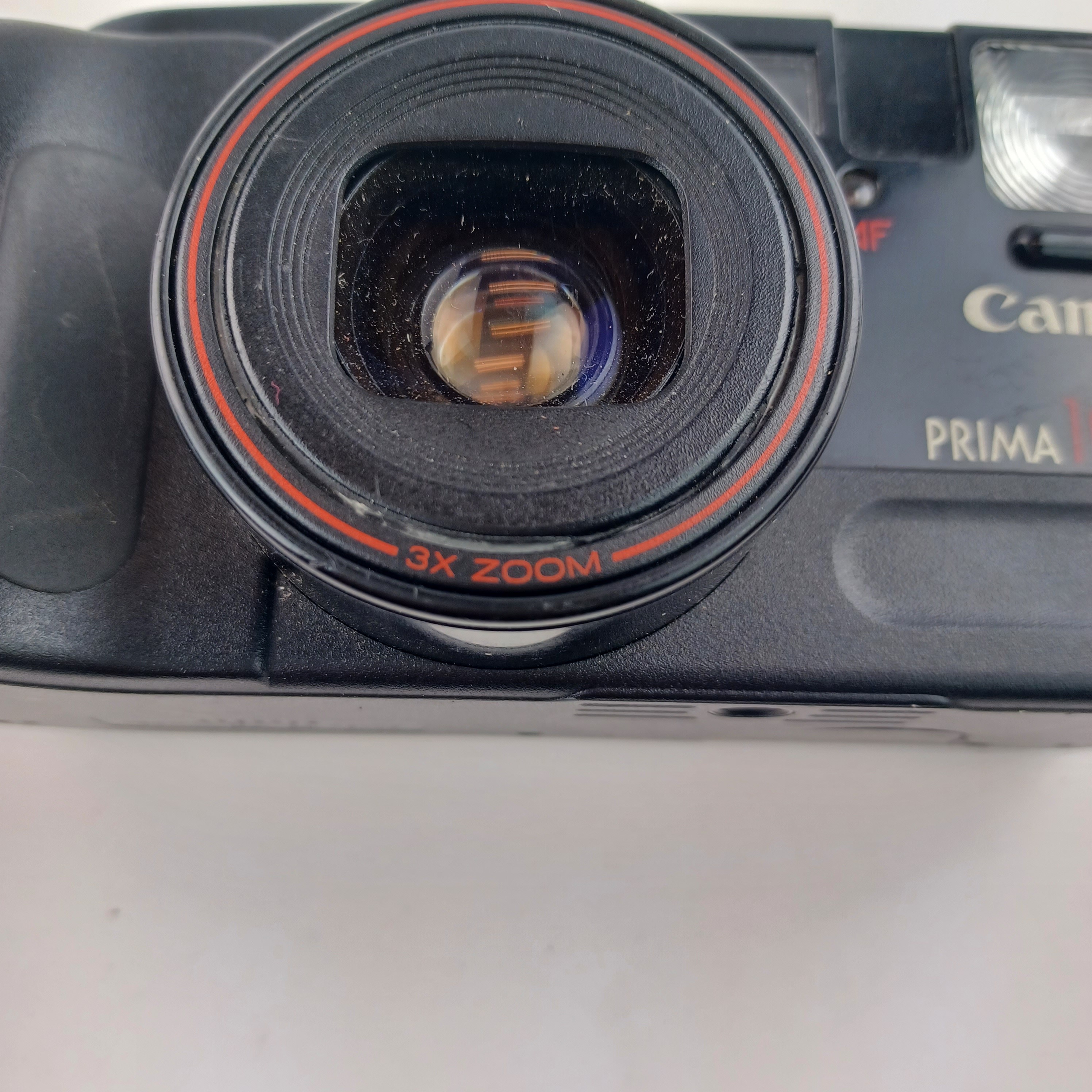 Voir photo 5 de Appareil photo Canon Prima 105 avec batterie lithium KL2CR5 sans chargeur, pellicule dedans, zoom 35-105, flash intégré, mode yeux rouges, retardateur et rafale, avec pochette et mode d'emploi Appareil photo Canon Prima 105 avec batterie lithium KL2CR5 sans chargeur, pellicule dedans, zoom 35-105, flash intégré, mode yeux rouges, retardateur et rafale, avec pochette et mode d'emploi Très bon état reconditionné photo 5