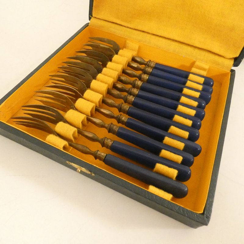 Voir photo 2 de Coffret de 11 anciennes fourchettes à gâteau en métal doré et manches en bakélite bleue Coffret de 11 anciennes fourchettes à gâteau en métal doré et manches en bakélite bleue Bon état reconditionné photo 2
