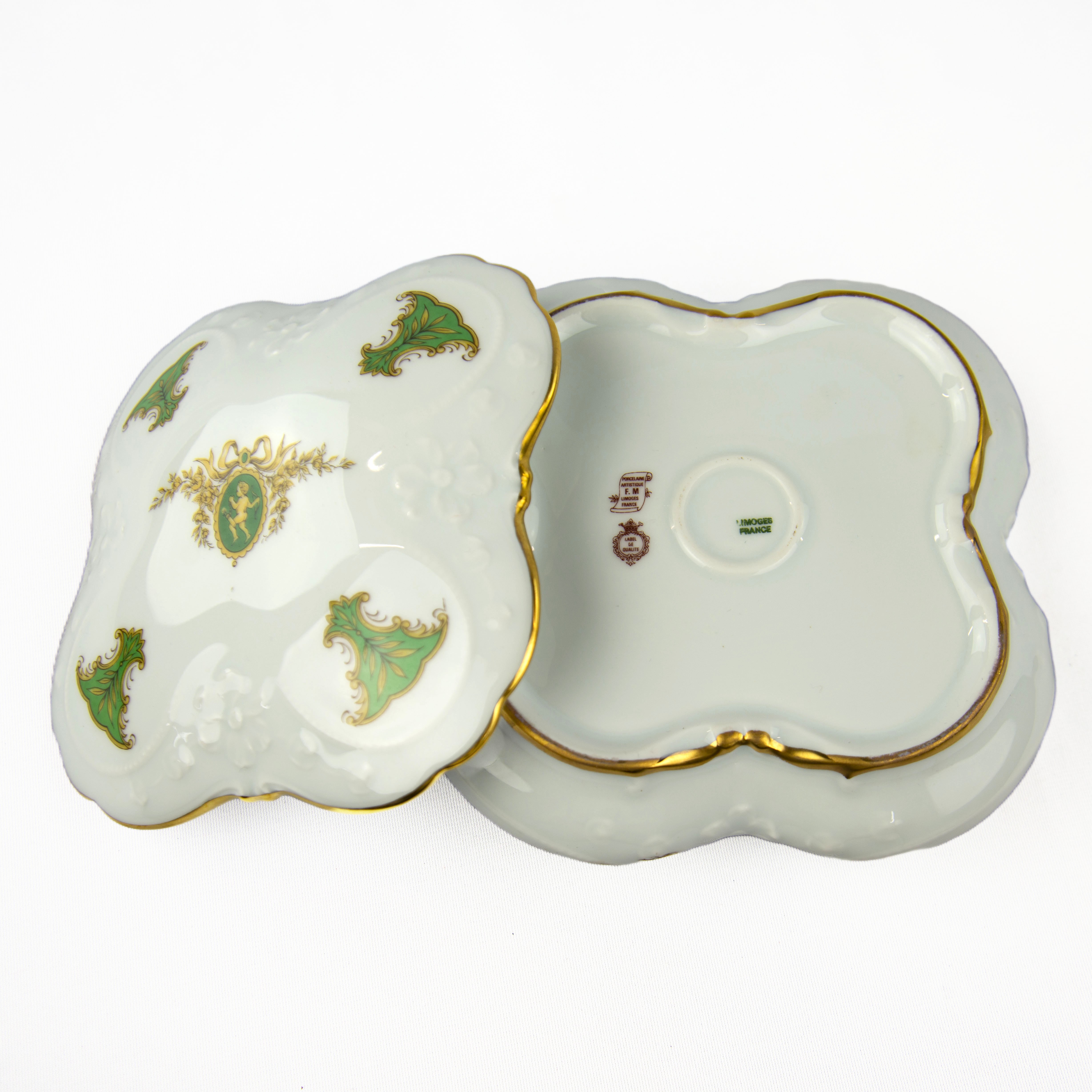 Voir photo 4 de Grande bonbonnière en porcelaine de Limoges artistique Label de Qualité F.M. de 16x16 blanche à motifs royaux vert et avec un médaillon avec un ange jaune Grande bonbonnière en porcelaine de Limoges artistique Label de Qualité F.M. de 16x16 blanche à motifs royaux vert et avec un médaillon avec un ange jaune Très bon état reconditionné photo 4