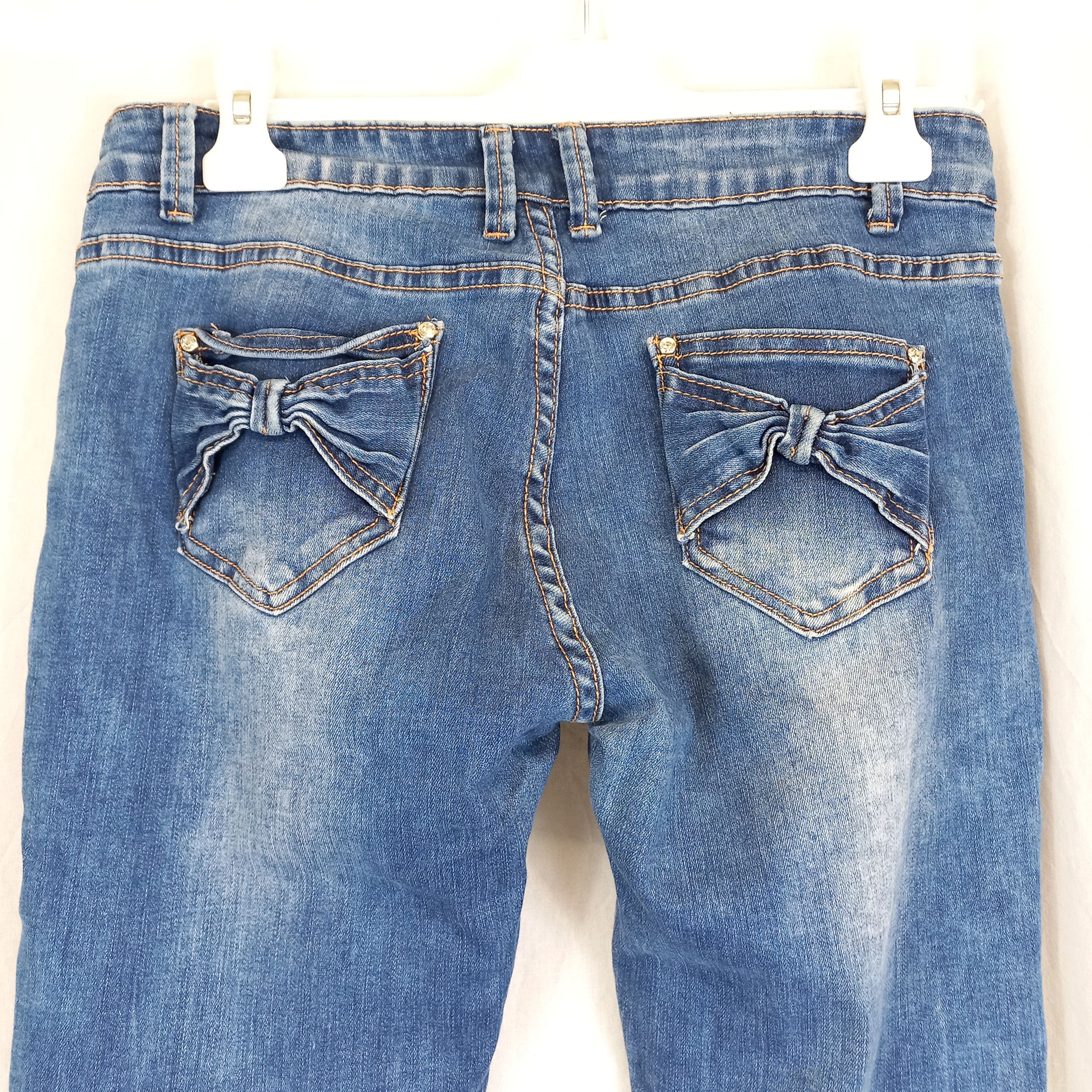Voir photo 3 de Jeans bleu délavé avec nœuds et strass sur poches arrière "miss rj " T42 Jeans bleu délavé avec nœuds et strass sur poches arrière "miss rj " T42 Très bon état reconditionné photo 3