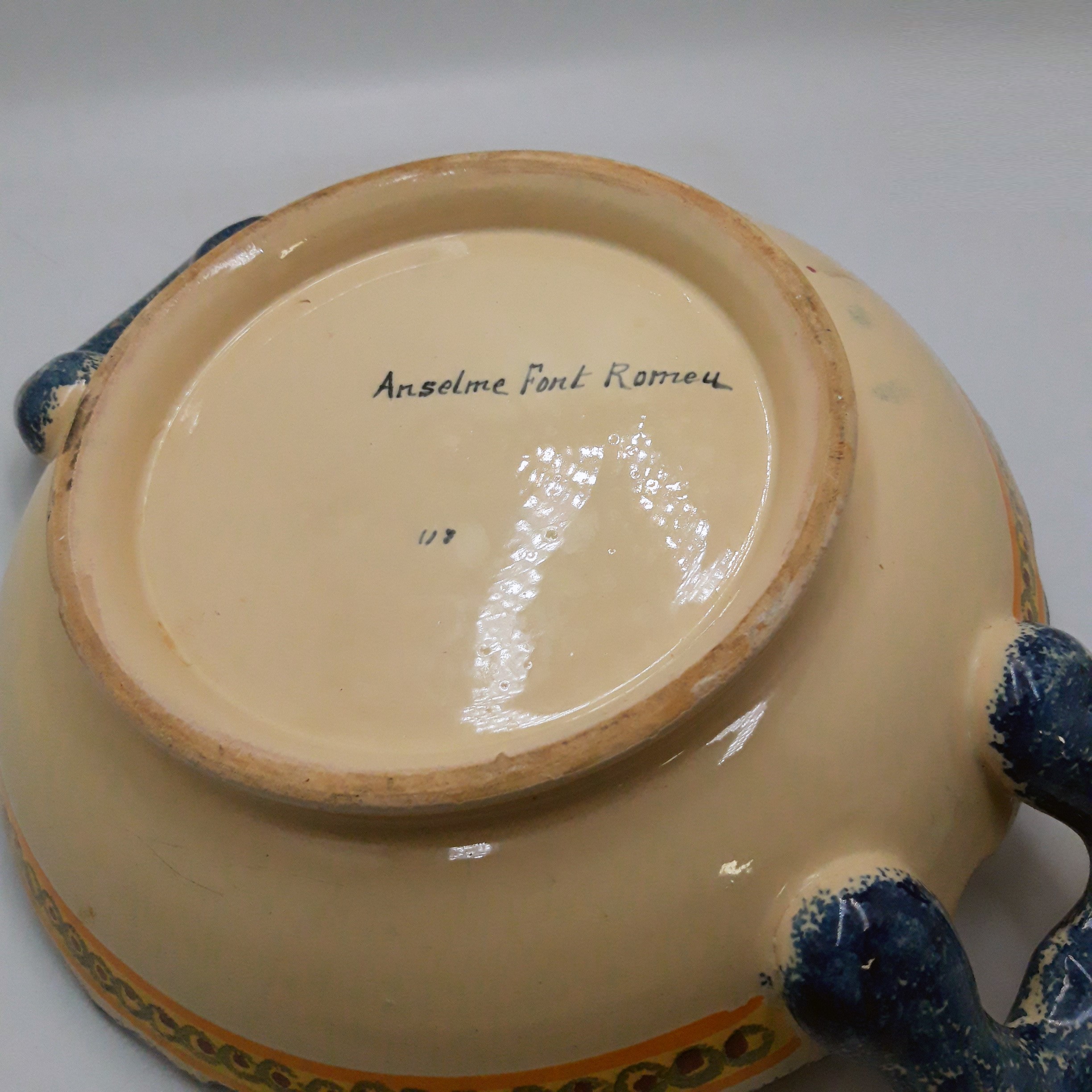 Voir photo 3 de Plat en faïence colorée avec anses signé ‘’Anselme Font Romeu’’, Artisanat Catalan. Plat en faïence colorée avec anses signé ‘’Anselme Font Romeu’’, Artisanat Catalan. Très bon état reconditionné photo 3
